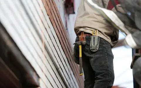 Technicien équipé de sa ceinture à outils devant un mur en cours d'équipement